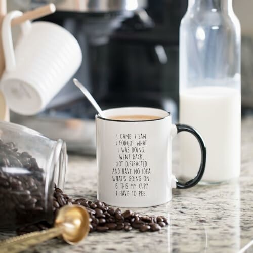 Coffee mug with humorous text on kitchen counter with coffee beans and milk.