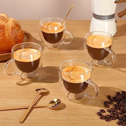 Four espresso cups with coffee on a wooden table.