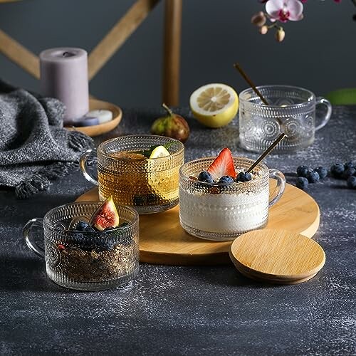 Glass mugs with desserts and tea on a wooden tray.