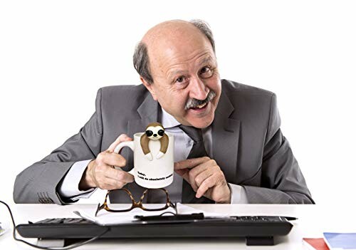 Man in suit holding sloth-themed mug at desk.