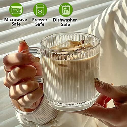 Hands holding ribbed glass mug with iced coffee, labeled microwave, freezer, and dishwasher safe.